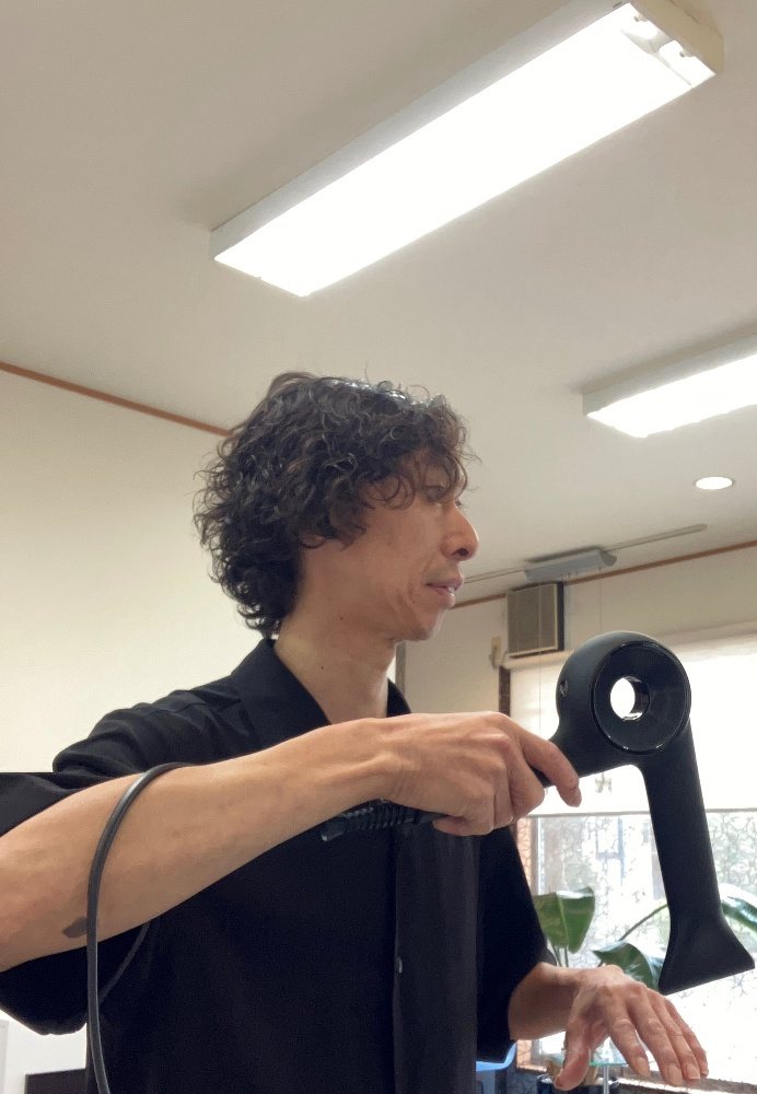 ドライヤーでお客様の髪を乾かす代表の高野 光浩